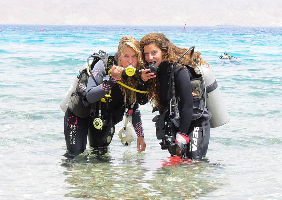 צוללות-נושמות-ממיכלי-אוויר-מועשרי-חמצן שתי צוללות עומדים במים רדודים ומחזיקות ווסתים בפה